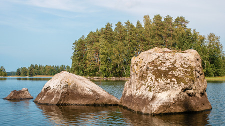 Rocks and forested iceland in Finnish lake surrounded by lush forestsの写真素材