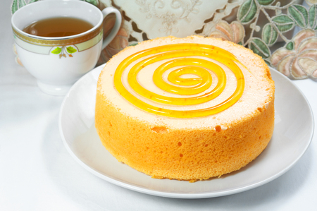 Sponge orange cake dessert with tea cup on tableの写真素材