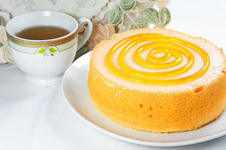 Sponge orange cake dessert with tea cup on tableの写真素材