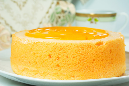 Closeup sponge orange cake dessert with tea on tableの写真素材