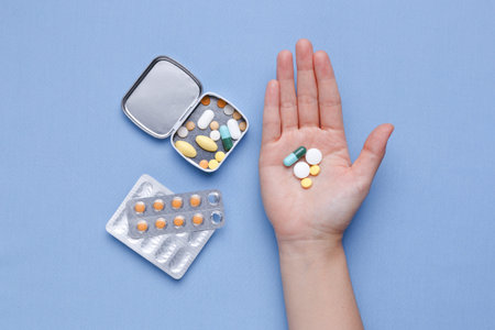 Pills in box and medicine pack with hand holding pills