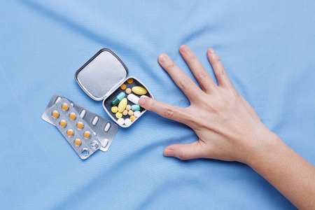 Closeup hand trying to take pills with pain and suffer from illnessの写真素材