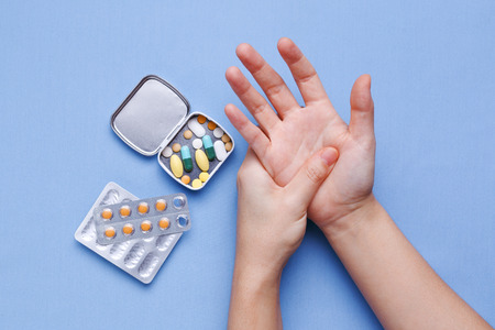 Woman hand with joint pain and pills on tableの写真素材