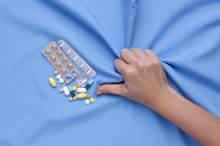 Closeup hand with pain and suffer from illness with medicine pillsの写真素材