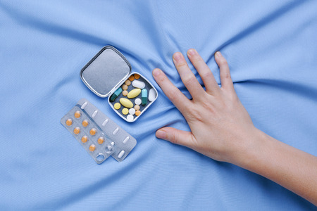 Closeup hand with pain and suffer from illness with medicine pillsの写真素材