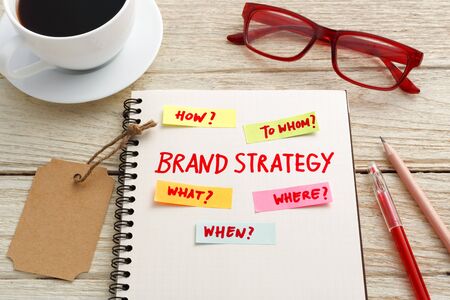 Brand marketing strategy concept with kraft tag, eye glasses and coffee on office deskの写真素材