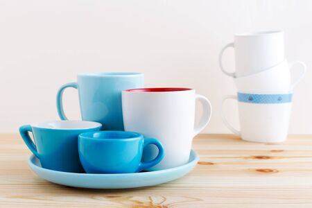 Blue cups and white mug on plate on wooden tableの写真素材