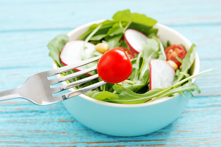 Healthy eating with salad closeup tomato with hand holding forkの写真素材