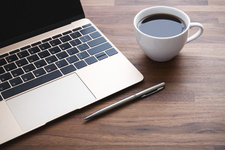 Office desk with laptop and coffee cup and penの写真素材