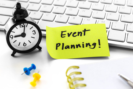 Event planning word on notepad with clock on white computer deskの写真素材
