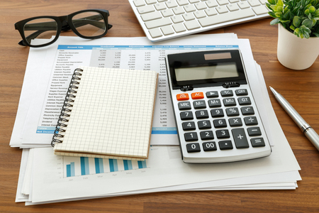 Financial accounting with calculator and blank notebook on wooden tableの写真素材