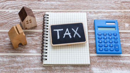 Tax sign on notebook with house model and calculator for property tax conceptの写真素材