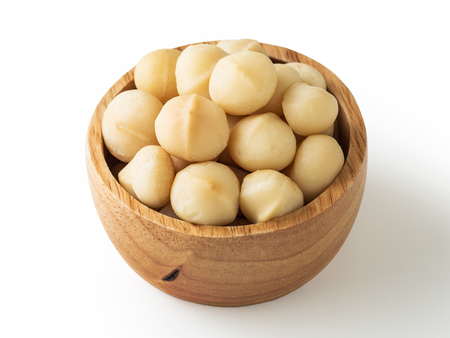 Macadamia nuts in wooden bowl on white backgroundの写真素材