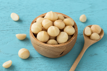Macadamia nuts in bowl on blue wooden tableの写真素材