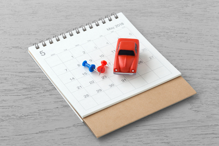 Calendar and red toy cars with calendar pins on wooden tableの写真素材