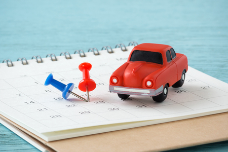 Red toy car and pins on calendarの写真素材