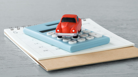Toy car on caculator and calendar on wooden tableの写真素材