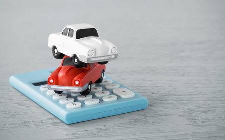 Toy cars on calculator on wooden backgroundの写真素材