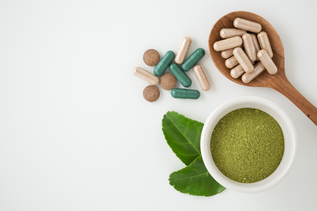Herbal medicine in capsules with kaffir lime leaf on white backgroundの写真素材