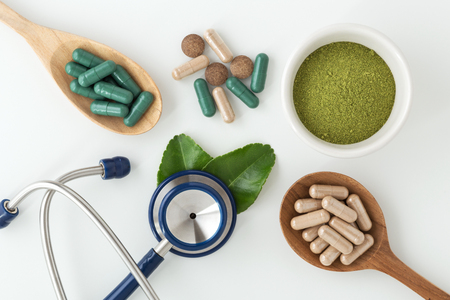Herbal medicine in capsules with kaffir lime leaf and  stethoscope on white backgroundの写真素材