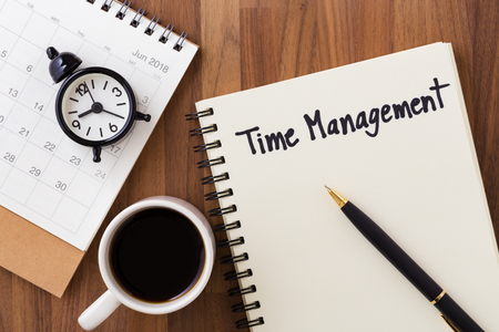 Time management concept with clock on calendar and notebook with pen from top viewの写真素材