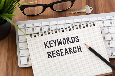 Keywords research words on notebook with computer keyboardの写真素材