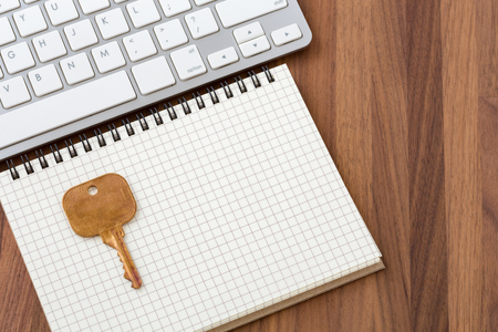Key on blank notebook with computer keyboard on wooden deskの写真素材