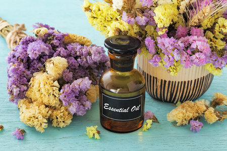 Bottle of essential oil with flower on blue wooden tableの写真素材