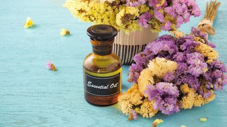 Bottle of essential oil with flower on blue wooden backgroundの写真素材
