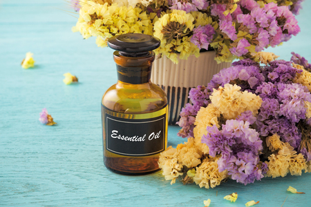 Bottle of essential oil with flower on blue wooden tableの写真素材