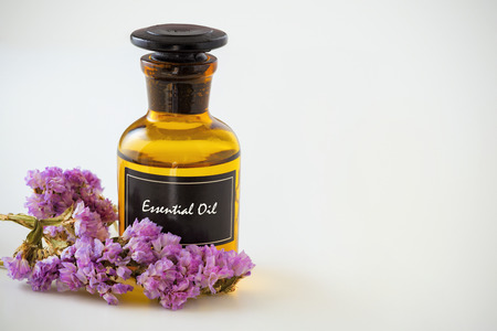 Bottle of essential oil with flower on white backgroundの写真素材