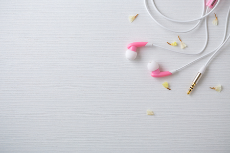 Earphones with flower on white wooden desk backgroundの写真素材