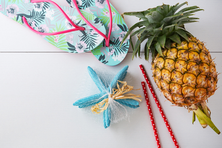 Summer beach vacation background with pineapple, flip-flops and star shellの写真素材