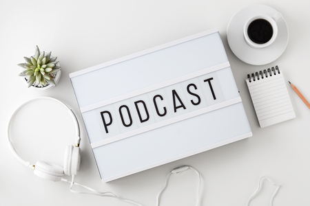 Podcast word on lightbox with headphones on white table, flat layの写真素材
