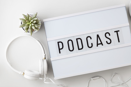 Podcast word on lightbox with headphones on white table, podcast conceptの写真素材