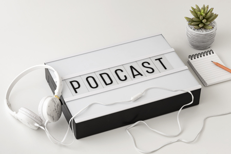 Podcast word on lightbox with headphones and notepad on white background, podcast conceptの写真素材