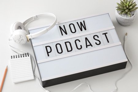 Now Podcast word on lightbox with headphones on white background, podcast conceptの写真素材