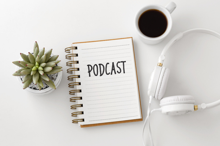 Podcast concept with headphones, notebook and coffee cup on white desk, top viewの写真素材