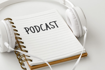 Podcast concept with headphones and podcast word on notebook on white backgroundの写真素材