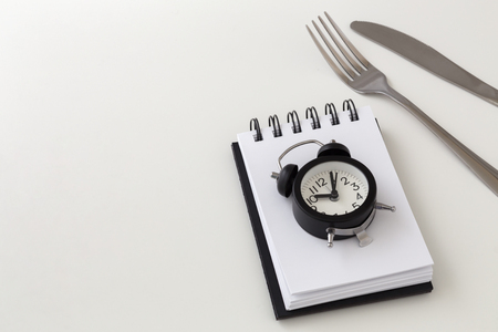 Clock with fork and knife, intermittent fasting and weight loss plan conceptの写真素材