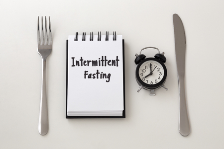 Intermittent fasting word on notepad with clock, fork and knife, weight loss planの写真素材