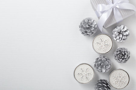 Christmas background with gift box and candle, white and silver decoration on wood table with space, top viewの写真素材