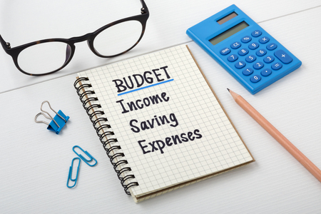 Personal budget planning concept with notebook and calculator on white wooden tableの写真素材