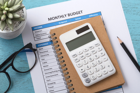 Monthly budget concept with white calculator on blue wood desk backgroundの写真素材