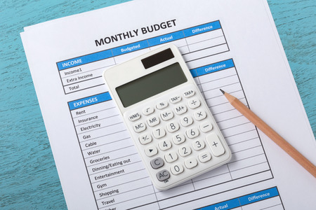 Monthly budget concept with white calculator and pencil on blue wood tableの写真素材