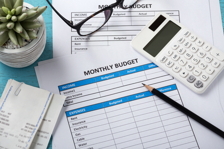 Monthly budget planning concept with white calculator and monthly budget sheet on blue deskの写真素材