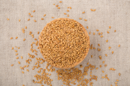 Golden flaxseed in wooden bowl, top viewの写真素材
