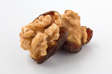 Walnuts and dried date fruit on white background, closeupの写真素材