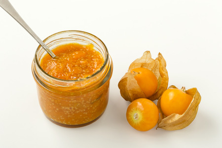 Golden berry jam in glass jar with golden berries isolated on white backgroundの写真素材