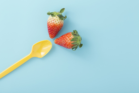 Strawberries with yellow spoon on light blue background, flat layの写真素材